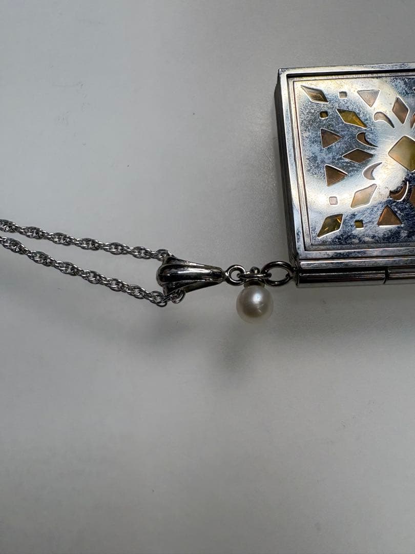 Mikimoto pearl necklace with decorative silver geometric pendant and removable rocket-shaped charm on adjustable chain