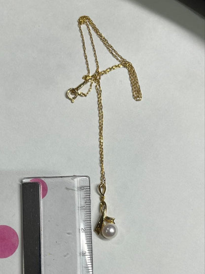 K18 gold necklace with single pearl and ribbon-shaped pendant on a white background
