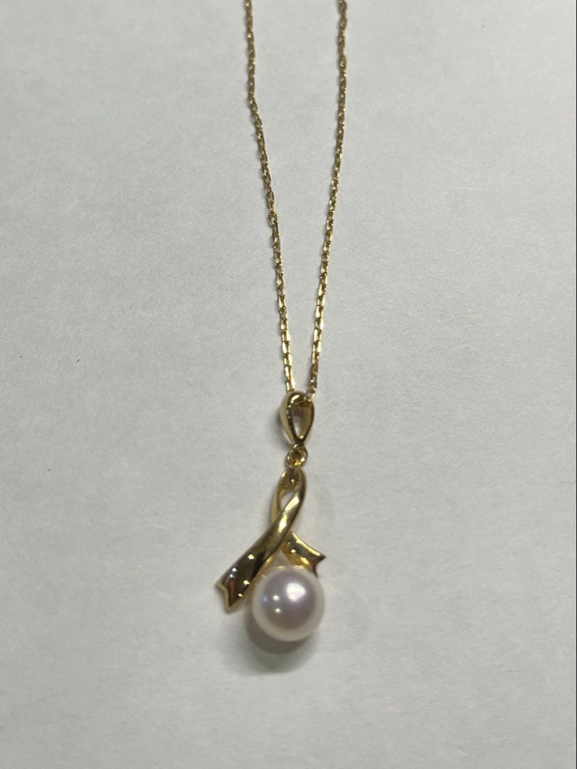 K18 gold necklace with single pearl and ribbon-shaped pendant on a white background