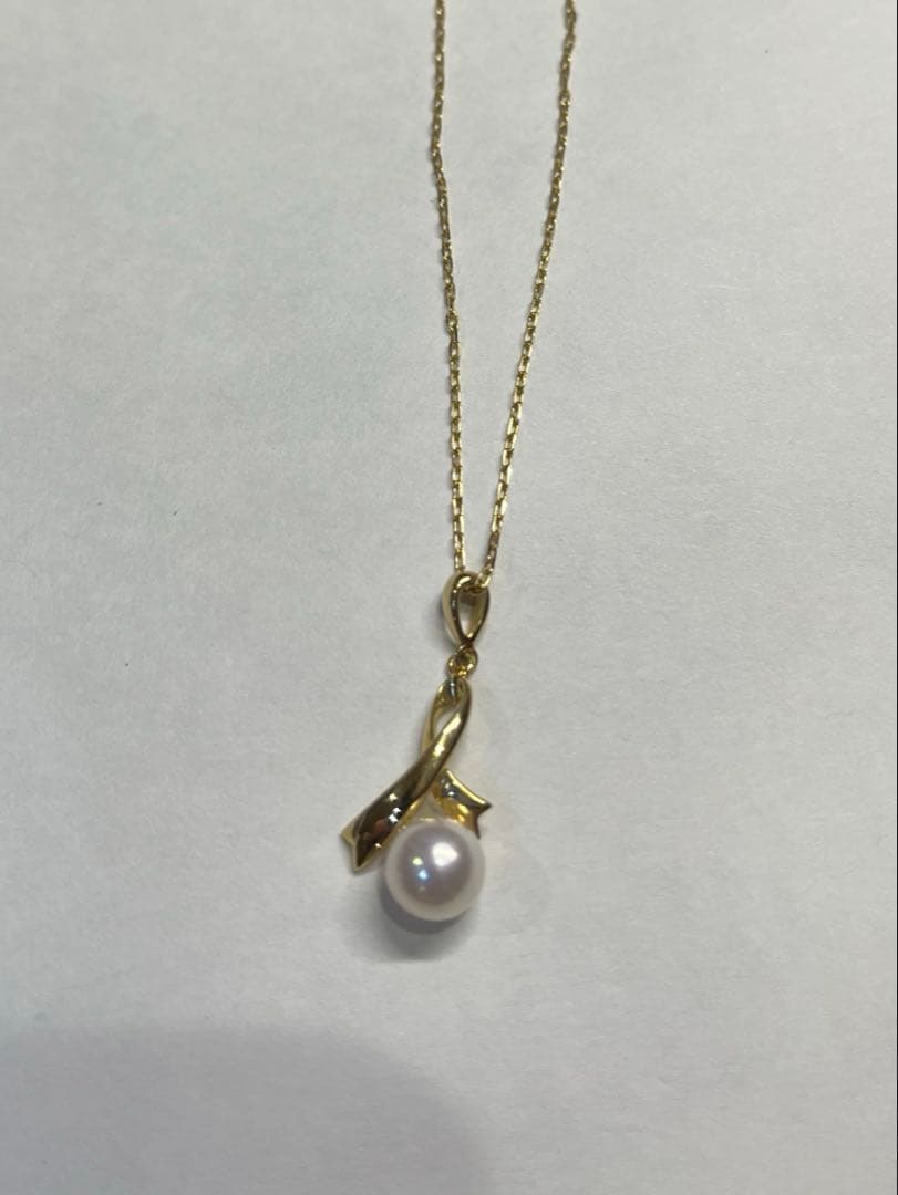 K18 gold necklace with single pearl and ribbon-shaped pendant on a white background