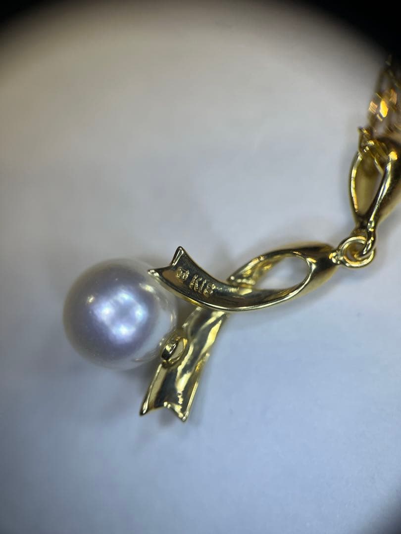 K18 gold necklace with single pearl and ribbon-shaped pendant on a white background
