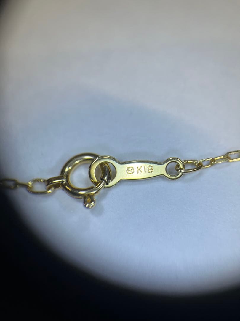 K18 gold necklace with single pearl and ribbon-shaped pendant on a white background