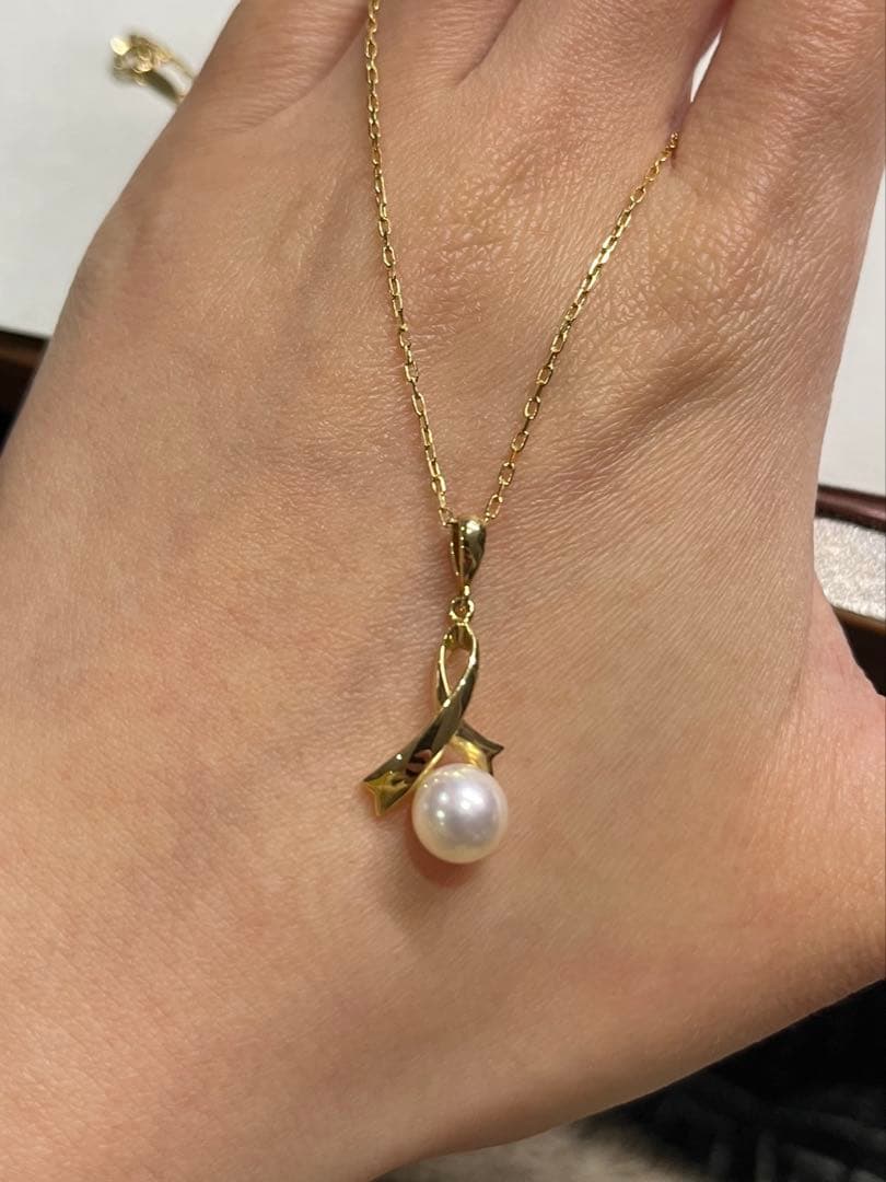 K18 gold necklace with single pearl and ribbon-shaped pendant on a white background