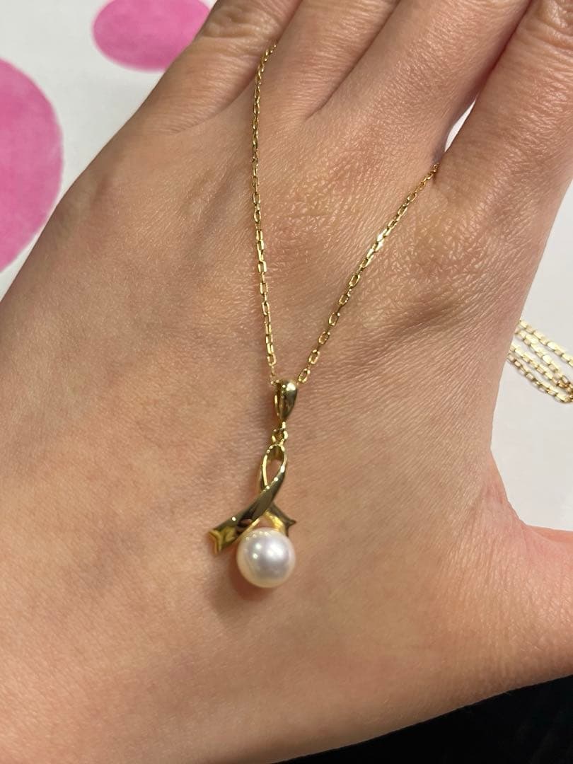 K18 gold necklace with single pearl and ribbon-shaped pendant on a white background