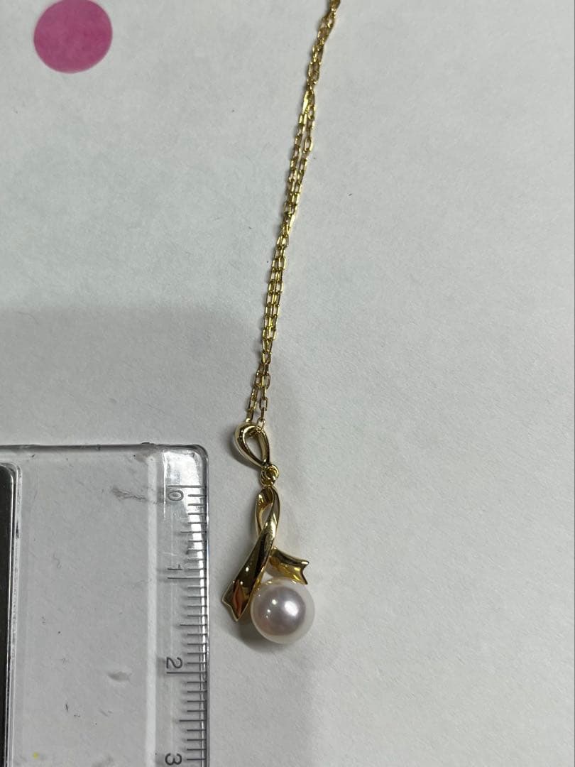 K18 gold necklace with single pearl and ribbon-shaped pendant on a white background