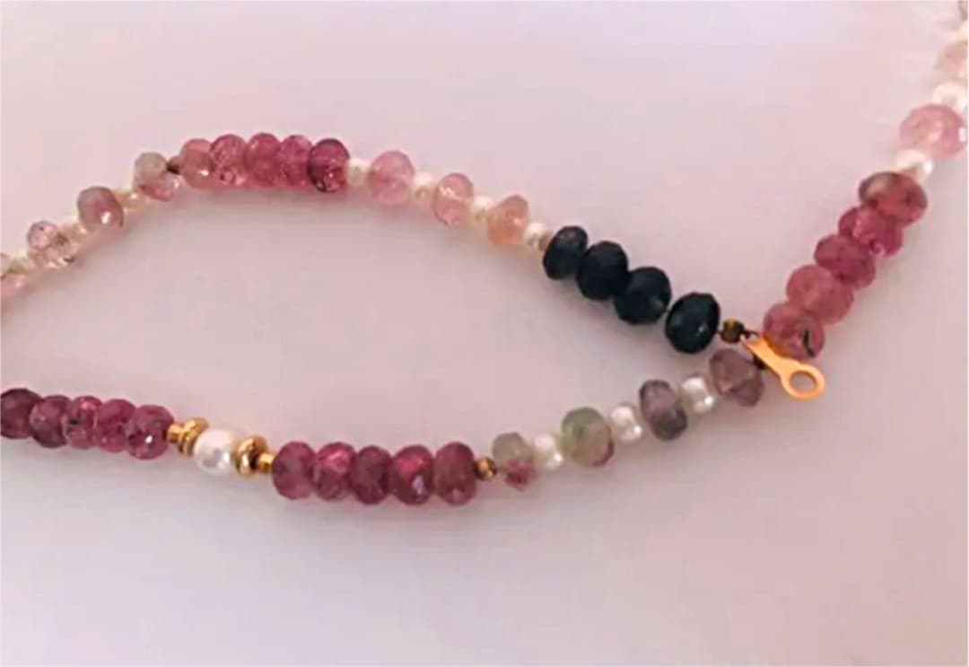 K18 gold necklace with 31 Akoya pearls and mixed cut tourmaline gemstones on display