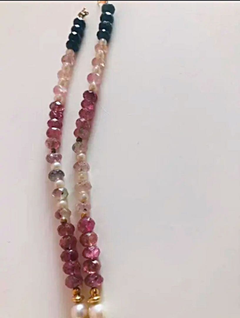 K18 gold necklace with 31 Akoya pearls and mixed cut tourmaline gemstones on display
