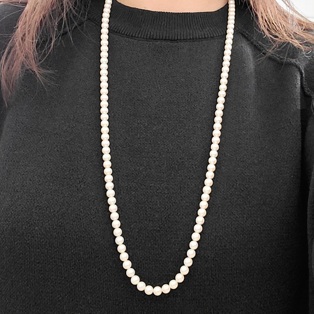 Akoya pearl necklace with 6mm pearls, 80cm length, silver clasp laid flat on white background