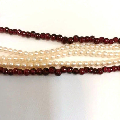 Five-row necklace with small round Akoya baby pearls and garnet stones showcasing high luster