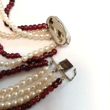 Five-row necklace with small round Akoya baby pearls and garnet stones showcasing high luster