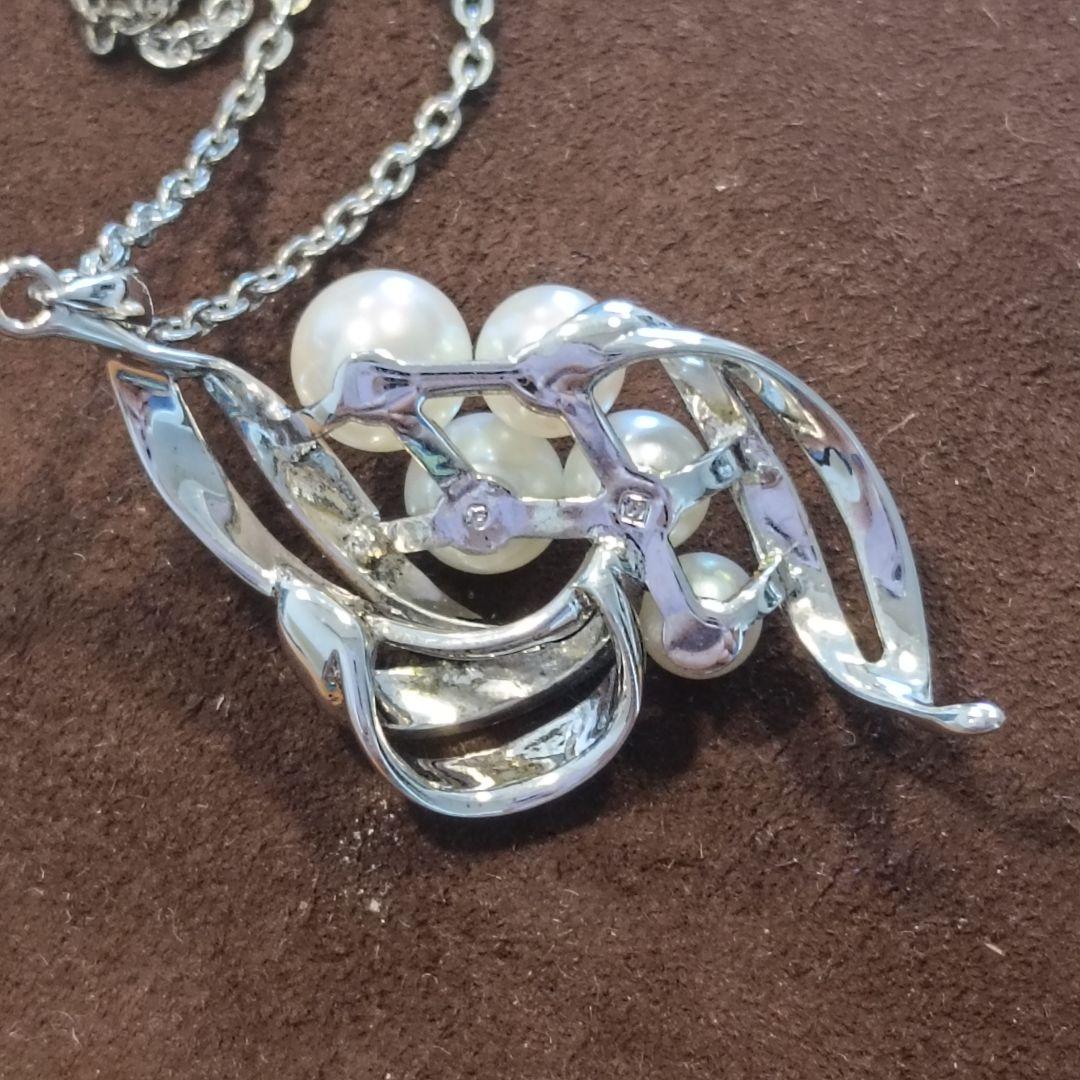 Mikimoto pearl necklace with grape-colored pearls and slightly discolored chain displayed on white background
