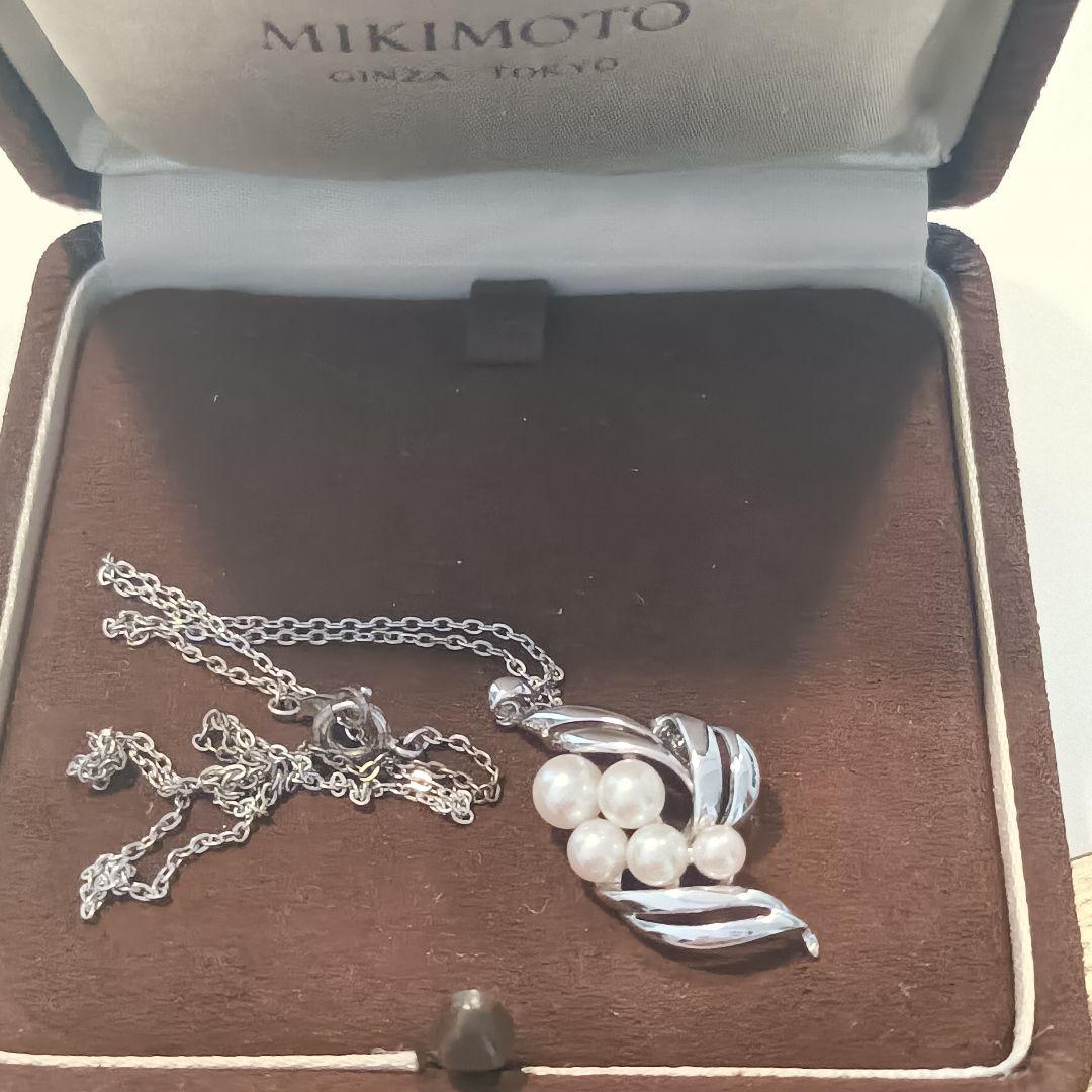Mikimoto pearl necklace with grape-colored pearls and slightly discolored chain displayed on white background