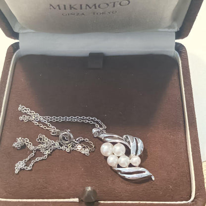 Mikimoto pearl necklace with grape-colored pearls and slightly discolored chain displayed on white background