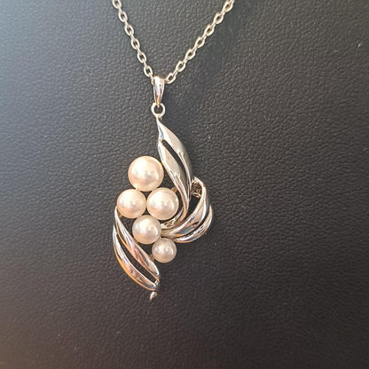 Mikimoto pearl necklace with grape-colored pearls and slightly discolored chain displayed on white background