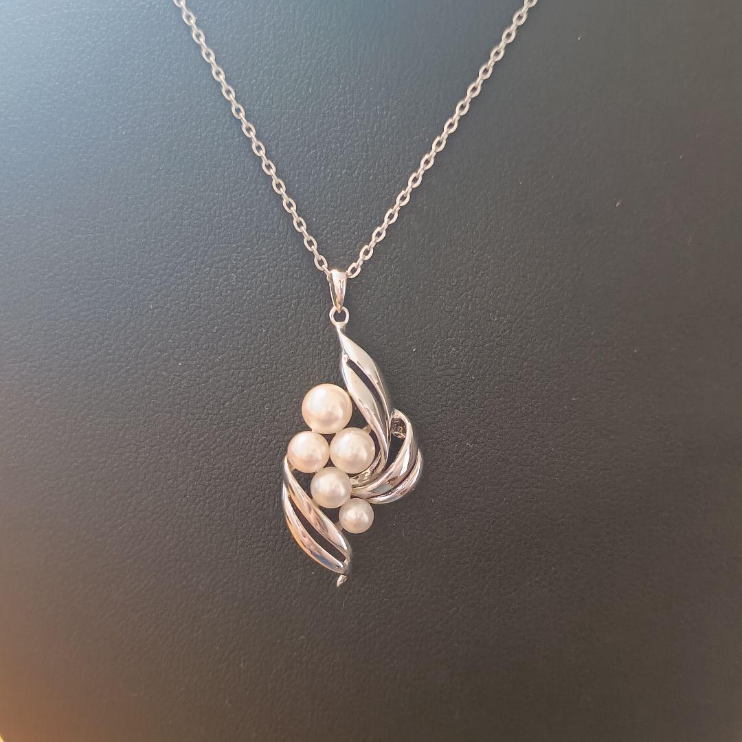 Mikimoto pearl necklace with grape-colored pearls and slightly discolored chain displayed on white background