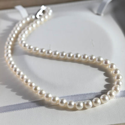Tasaki Akoya Pearl Necklace featuring 7mm round pearls and a silver clasp on a white background