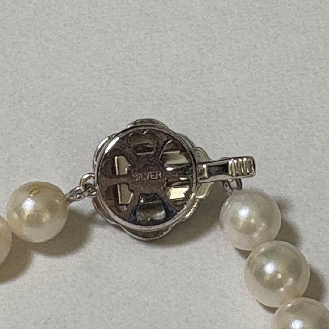 Akoya pearl necklace and matching earrings with silver engraved flower clasp on a white background