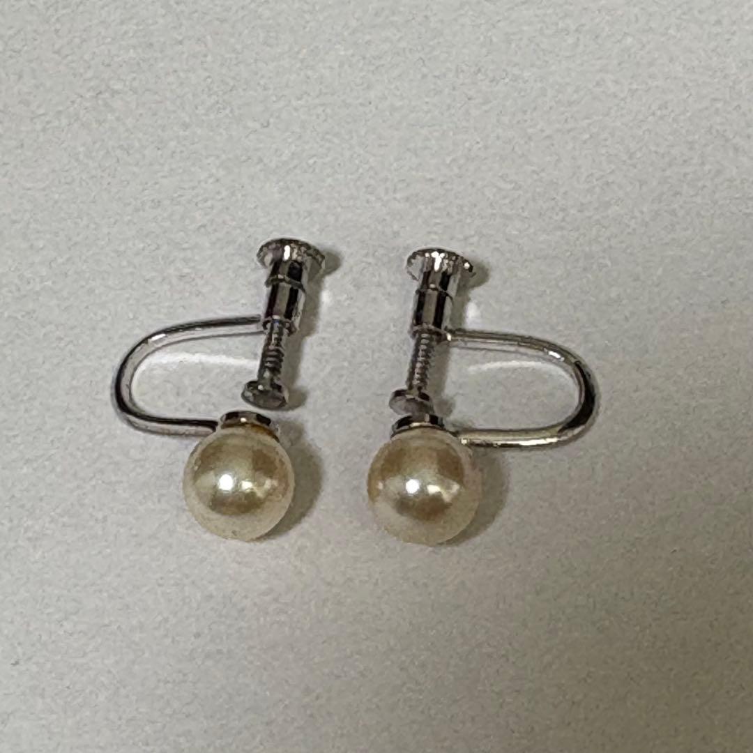 Akoya pearl necklace and matching earrings with silver engraved flower clasp on a white background