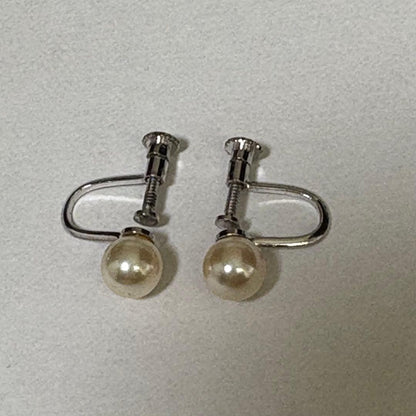 Akoya pearl necklace and matching earrings with silver engraved flower clasp on a white background