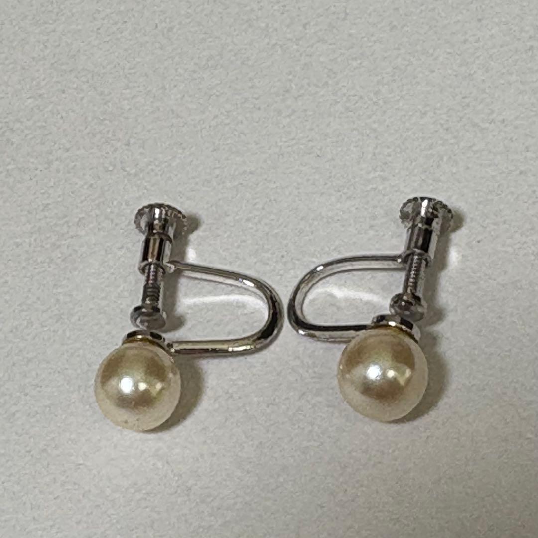 Akoya pearl necklace and matching earrings with silver engraved flower clasp on a white background