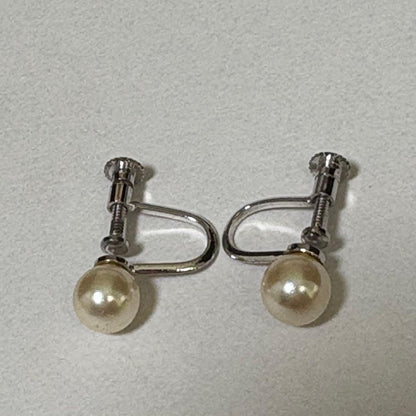 Akoya pearl necklace and matching earrings with silver engraved flower clasp on a white background
