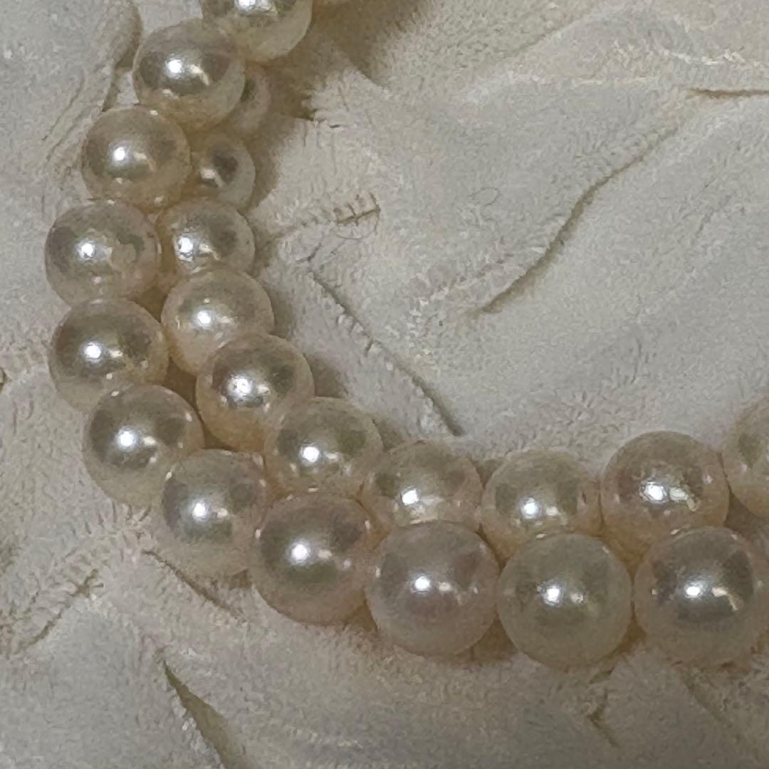 Akoya pearl necklace and matching earrings with silver engraved flower clasp on a white background
