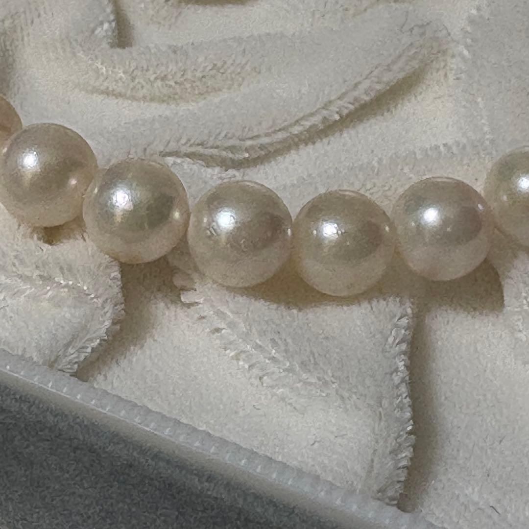 Akoya pearl necklace and matching earrings with silver engraved flower clasp on a white background