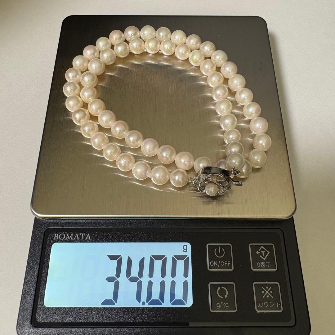 Akoya pearl necklace and matching earrings with silver engraved flower clasp on a white background