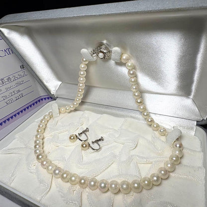 Akoya pearl necklace and matching earrings with silver engraved flower clasp on a white background