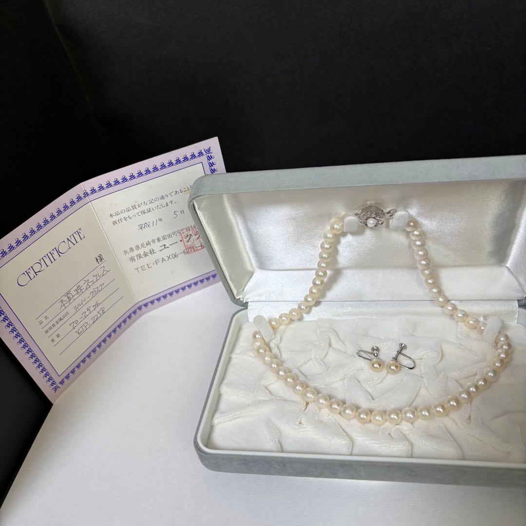 Akoya pearl necklace and matching earrings with silver engraved flower clasp on a white background