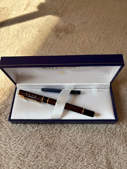 Brown WATERMAN fountain pen with logo, presented alongside a protective case and extra ink bottle