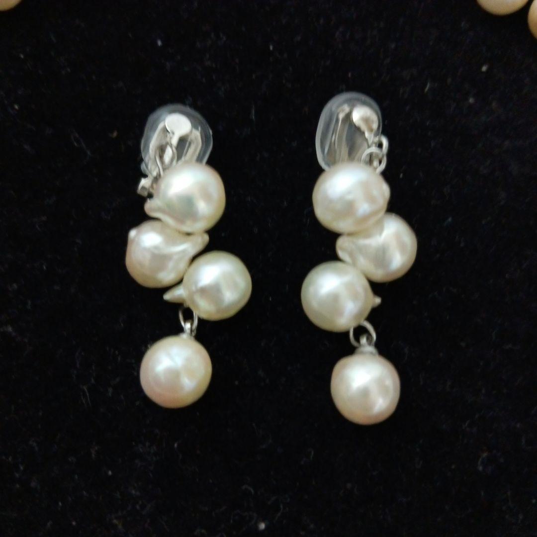 Akoya pearl necklace and earrings set with 8-9mm pearls and flower motif clasp on a white background
