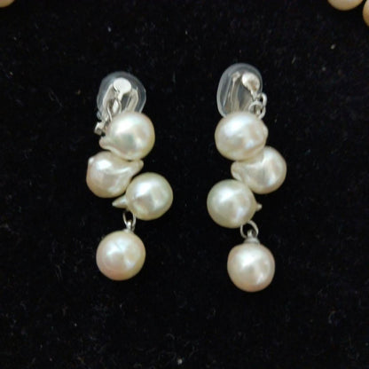 Akoya pearl necklace and earrings set with 8-9mm pearls and flower motif clasp on a white background