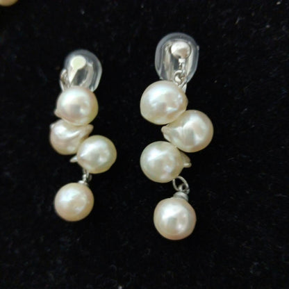 Akoya pearl necklace and earrings set with 8-9mm pearls and flower motif clasp on a white background