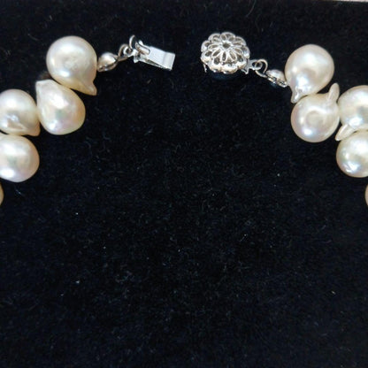 Akoya pearl necklace and earrings set with 8-9mm pearls and flower motif clasp on a white background