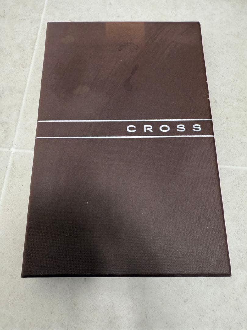 Two CROSS ballpoint pens in silver and black alongside a leather-like pen case