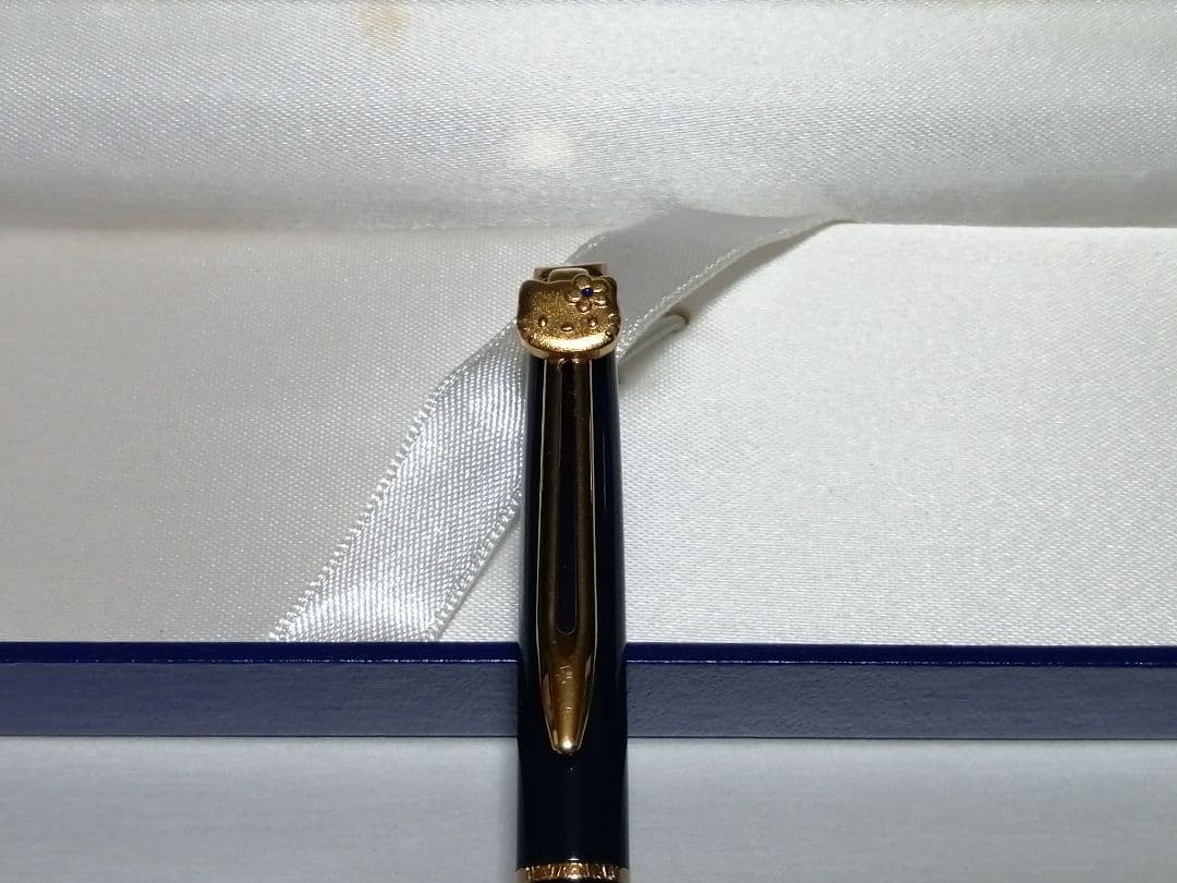 Hello Kitty Waterman ballpoint pen with extra ink refill, external box, and vintage storage case showing yellowing