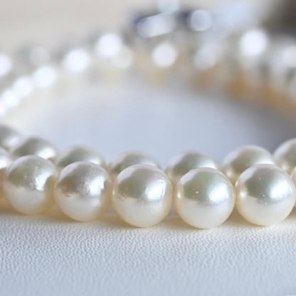 Takase Akoya pearl necklace with 7.5mm round pearls and silver ribbon clasp on a white background