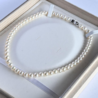 Takase Akoya pearl necklace with 7.5mm round pearls and silver ribbon clasp on a white background