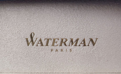 WATERMAN Paris ballpoint pen with silver wave pattern cap and black body beside a blue gift box