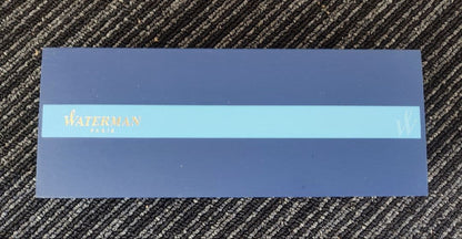 WATERMAN Paris ballpoint pen with silver wave pattern cap and black body beside a blue gift box