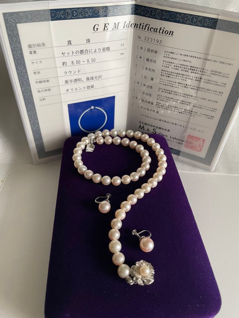 Akoya pearl necklace with approximately 43 cm length and matching round pearl screw-back earrings set on a white background