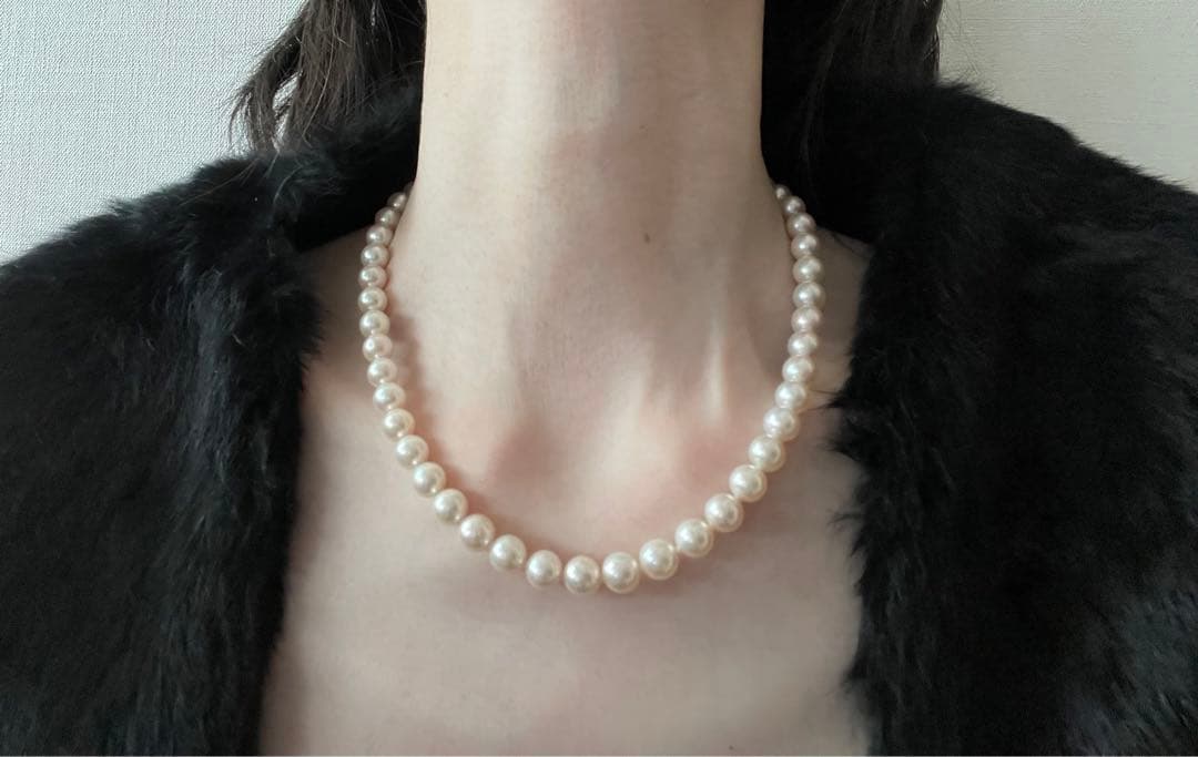 Akoya pearl necklace with approximately 43 cm length and matching round pearl screw-back earrings set on a white background