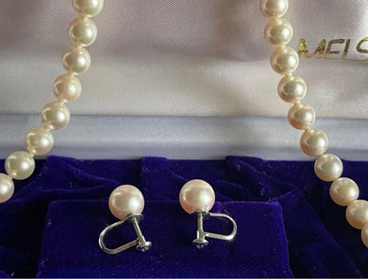 Akoya pearl necklace with approximately 43 cm length and matching round pearl screw-back earrings set on a white background