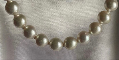 Akoya pearl necklace with approximately 43 cm length and matching round pearl screw-back earrings set on a white background