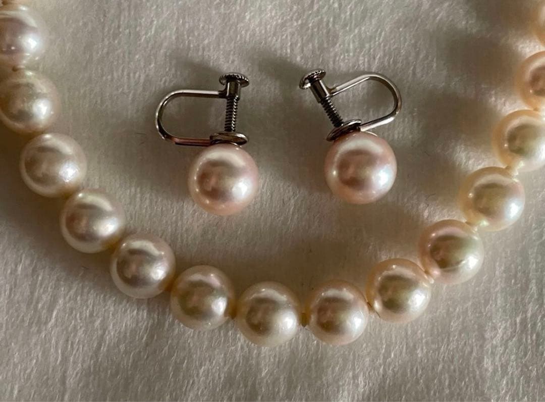 Akoya pearl necklace with approximately 43 cm length and matching round pearl screw-back earrings set on a white background
