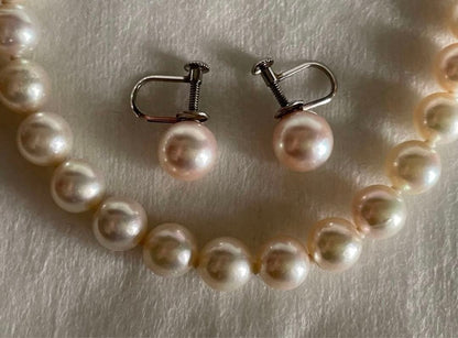 Akoya pearl necklace with approximately 43 cm length and matching round pearl screw-back earrings set on a white background