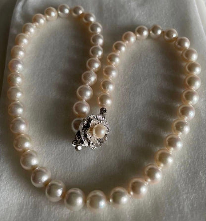 Akoya pearl necklace with approximately 43 cm length and matching round pearl screw-back earrings set on a white background