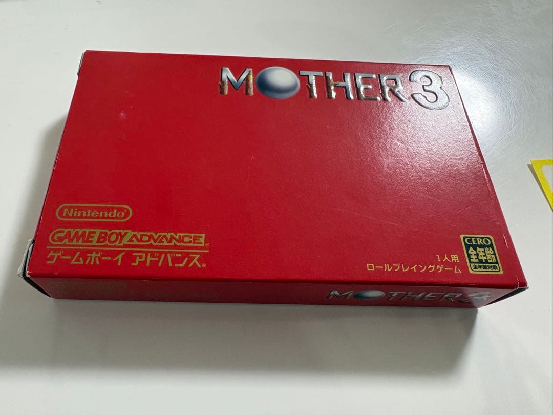 Game Boy Advance MOTHER3 game cartridge with original box and manual showing signs of aging and storage damage