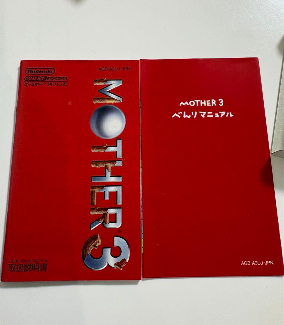 Game Boy Advance MOTHER3 game cartridge with original box and manual showing signs of aging and storage damage